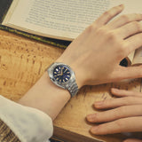 Seiko 5 SRE021K1 men's automatic watch with black dial, stainless steel case, and bracelet, displaying time and date.